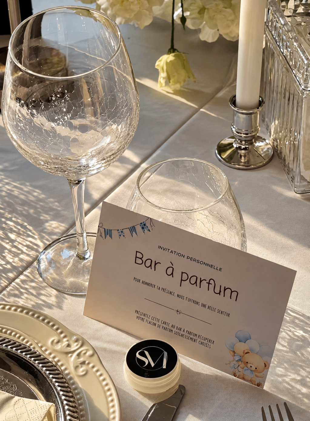 Carte d’invitation personnalisée posée sur une table dressée, bougie et verres