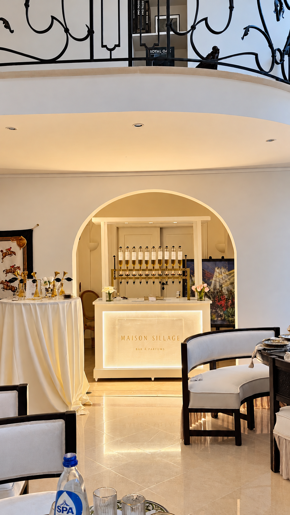 Bar à parfum Maison Sillage installé sous une arche voûtée, son comptoir rétroéclairé gravé Maison Sillage et ses flacons dorés